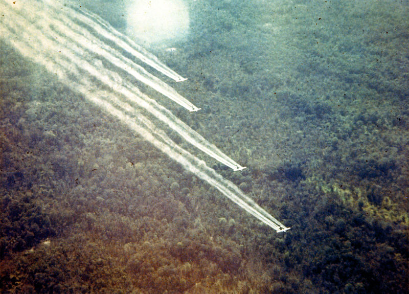 Four planes dispersing herbicide over a forest during the Vietnam War